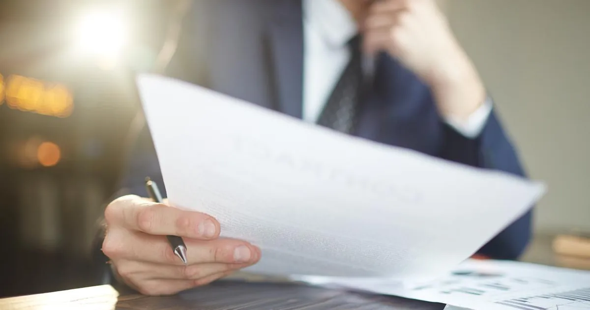 Entrepreneur relisant des documents administratifs, stylo en main, avant de choisir le statut juridique de son activité