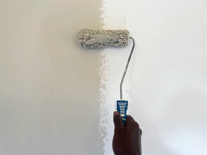 Peintre en bâtiment appliquant de la peinture au rouleau dans un intérieur