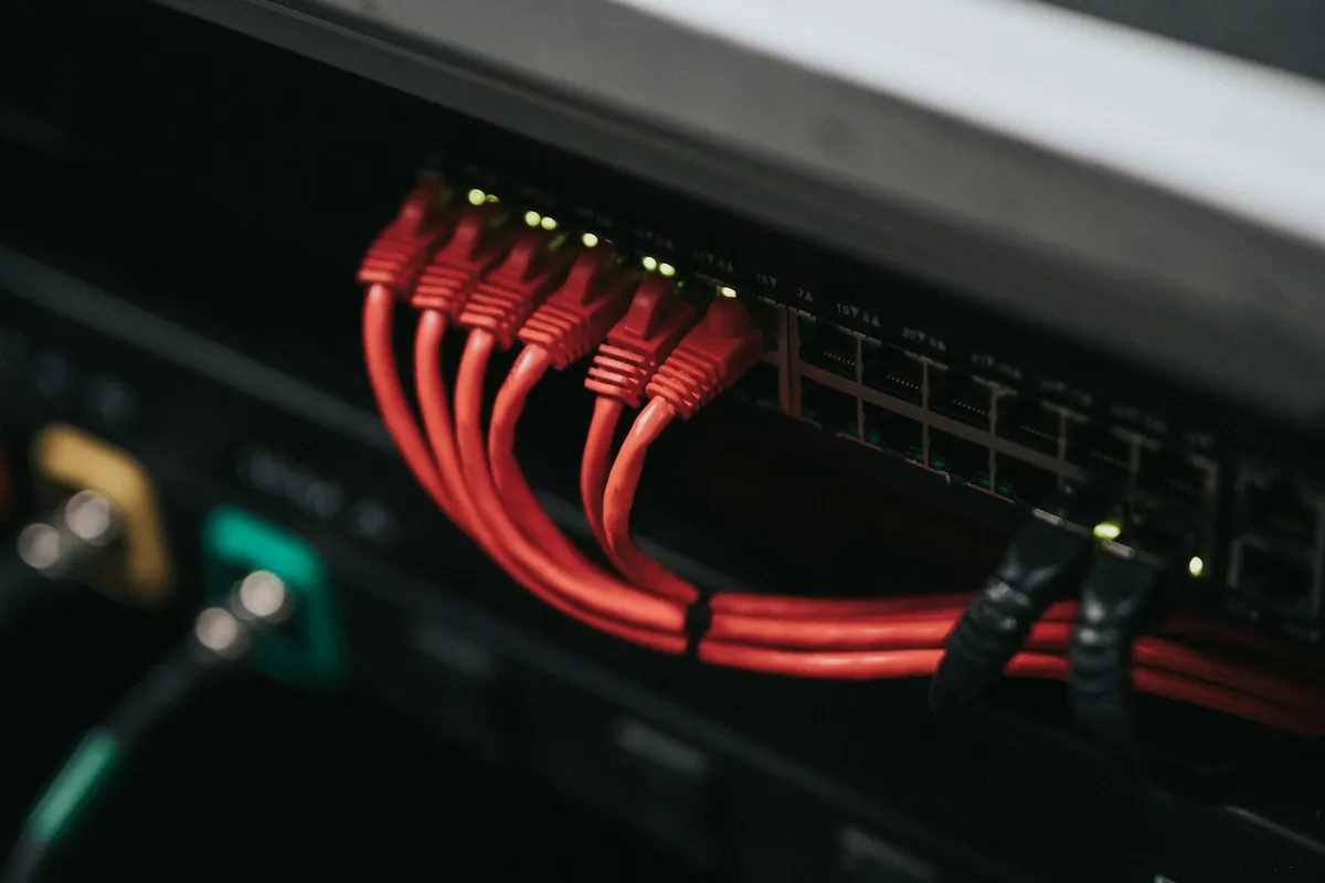 Câbles réseau reliés à une baie de serveurs illustrant l'infogérance et l'hébergement d'un site internet