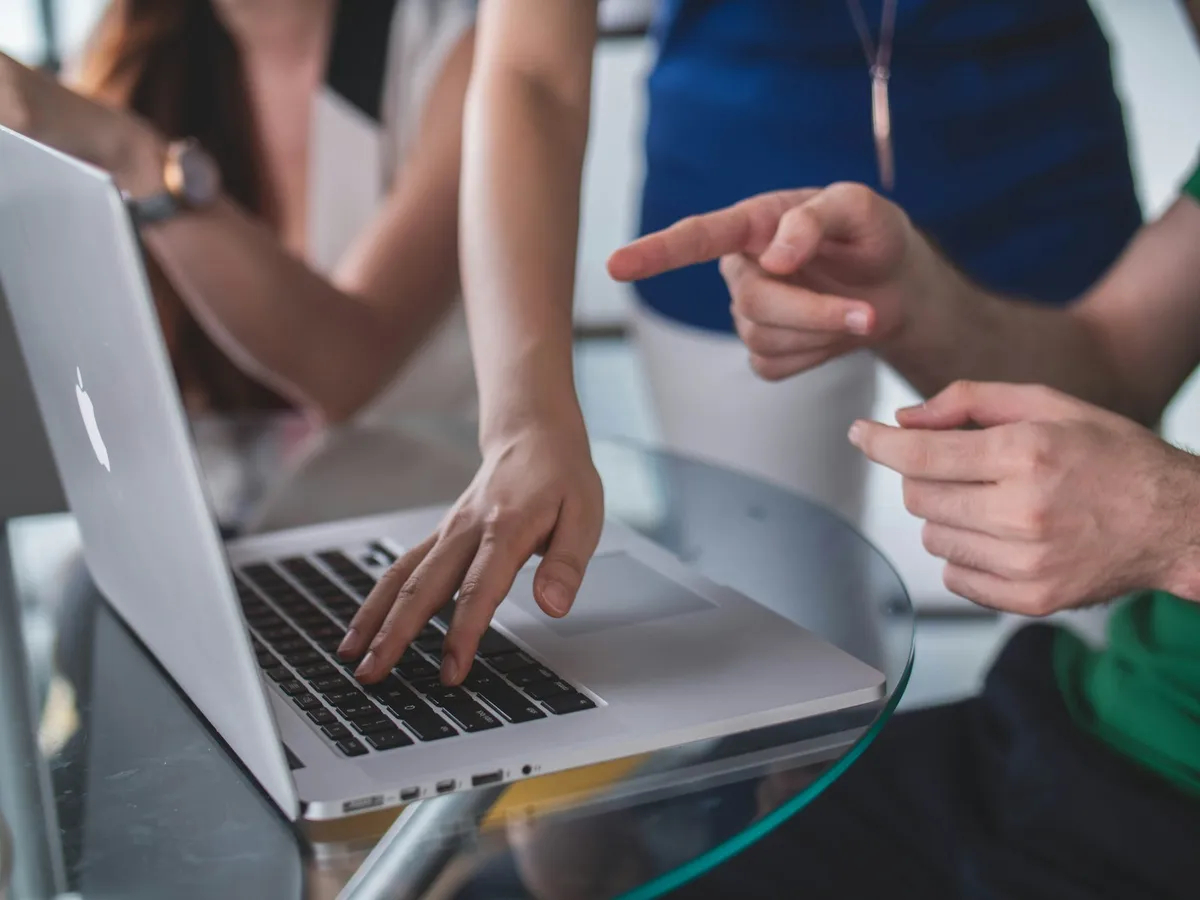 Équipe de PME et prestataire pointant l'écran d'un ordinateur portable lors du cadrage d'une application web