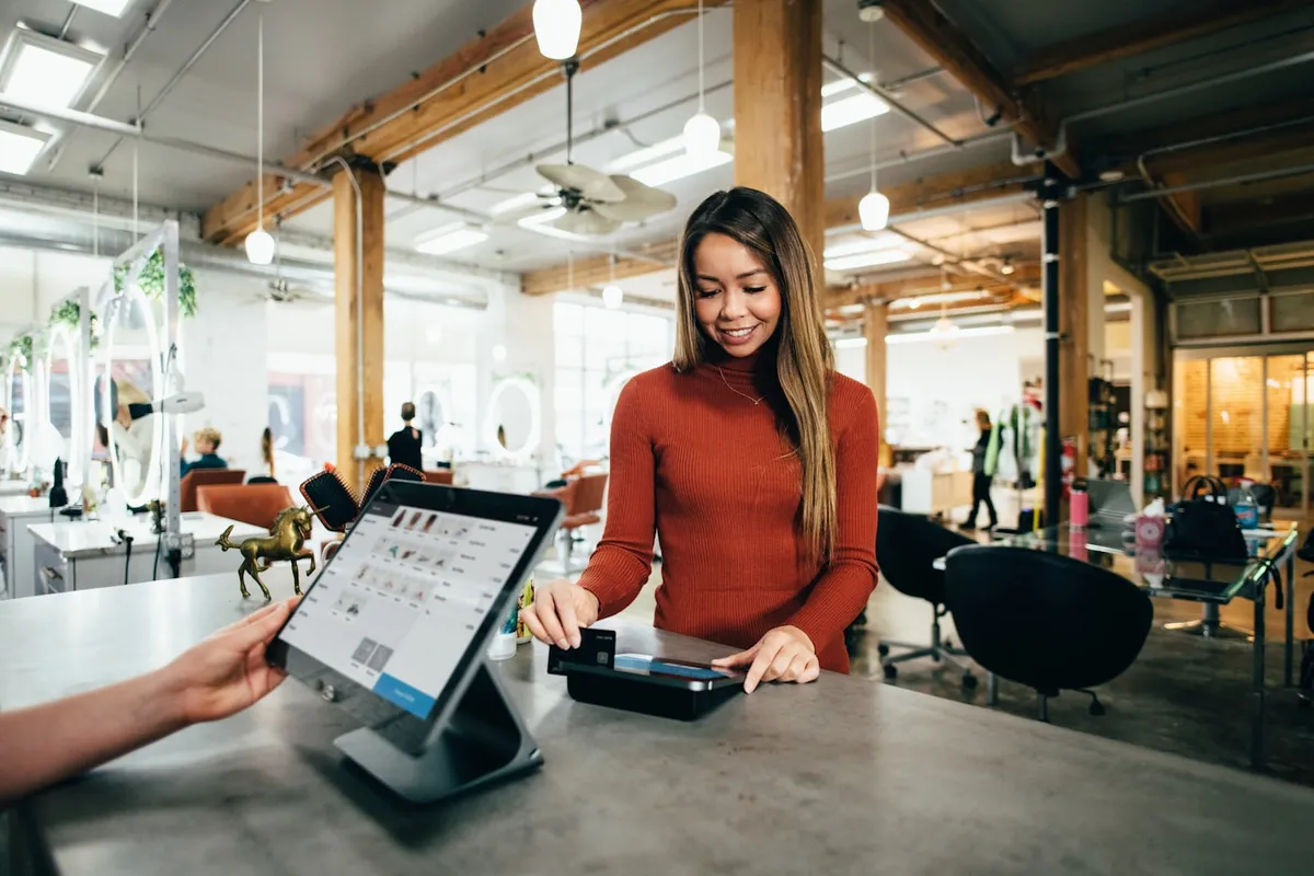 Cliente réglant son achat par carte bancaire via un terminal de paiement connecté à la boutique